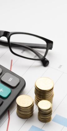 Glassess, coins, and calculator with the background of financial chart